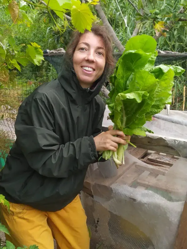 L'autrice sorridente mentre raccoglie verdure fresche nell'orto